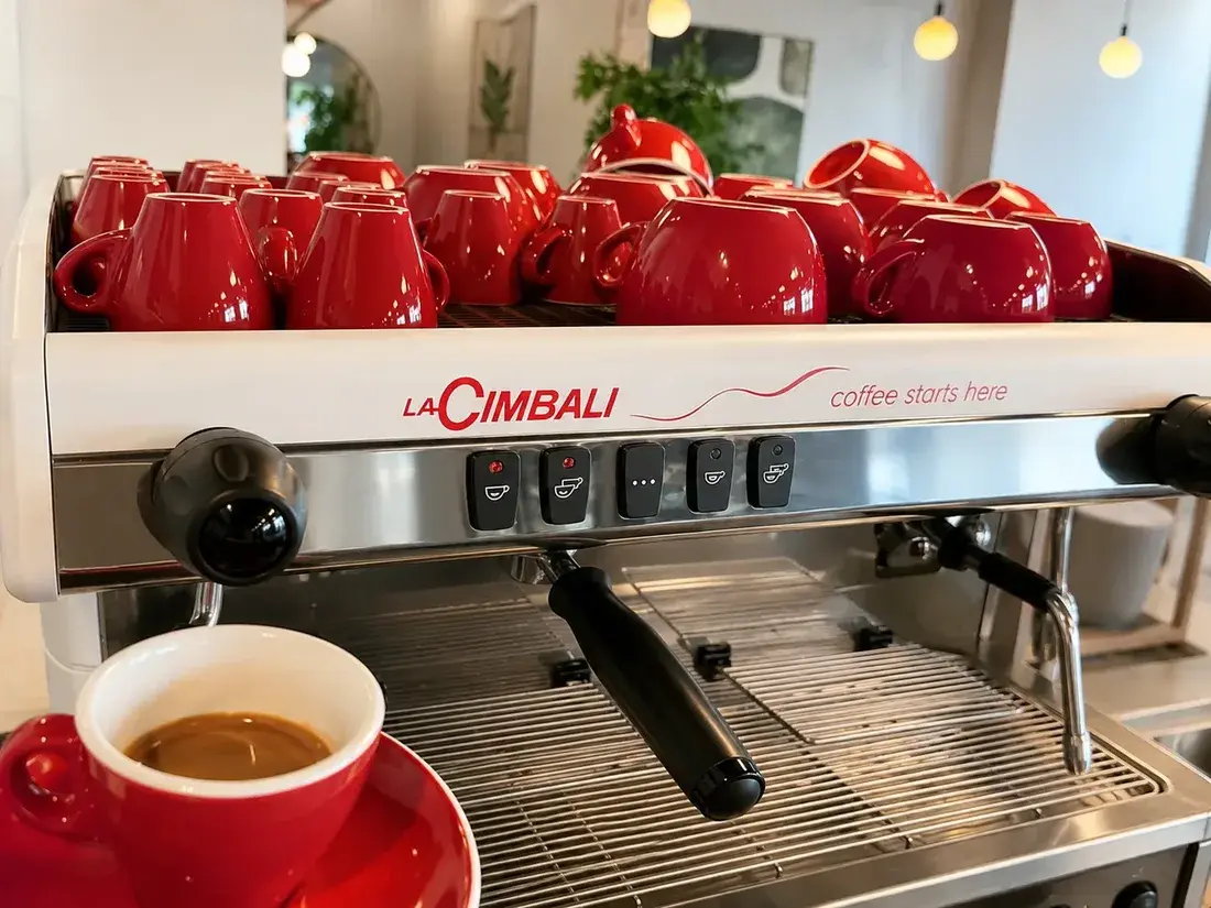La Cimbali-espressomaskin med röda espressokoppar och nybryggd espresso hos Kafé Kanel i Kristinehamn